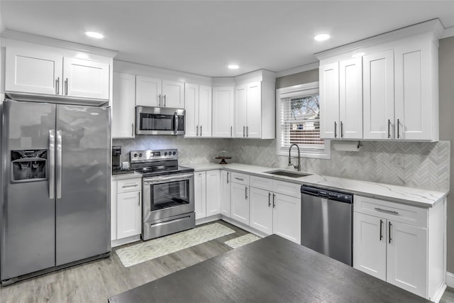 kitchen featuring stainless steel appliances, sink, white cabinets, and light hardwood / wood-style flooring