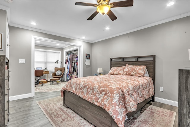 bedroom featuring hardwood / wood-style floors, ornamental molding, a walk in closet, ceiling fan, and a closet