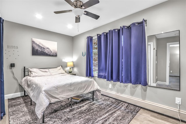 bedroom with a baseboard radiator, wood-type flooring, and ceiling fan