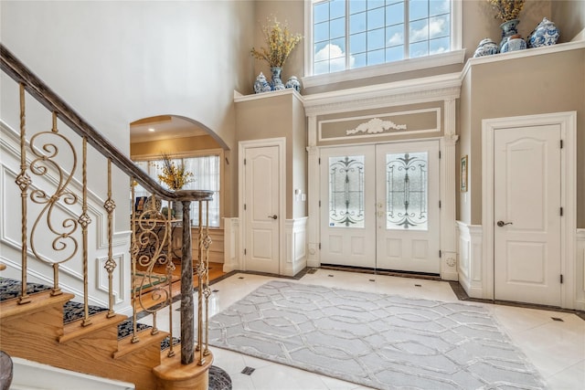 entryway with crown molding, a towering ceiling, and french doors