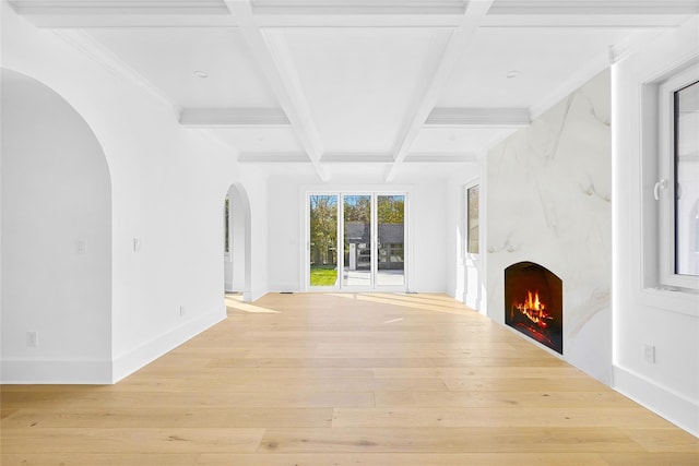 unfurnished living room with beam ceiling, coffered ceiling, light wood-type flooring, and a fireplace