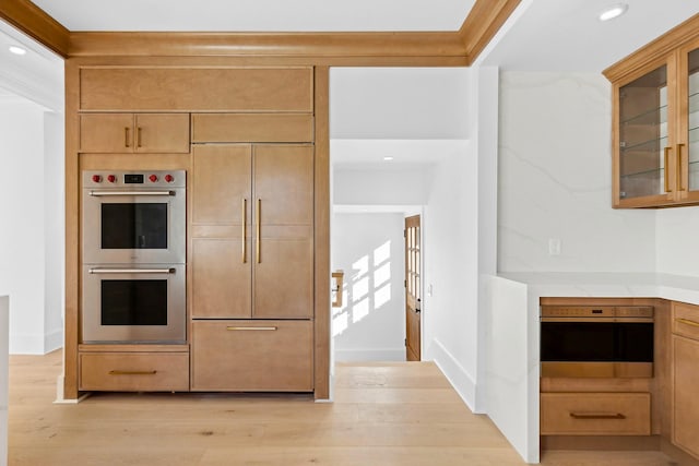 kitchen featuring double oven, crown molding, and light hardwood / wood-style floors