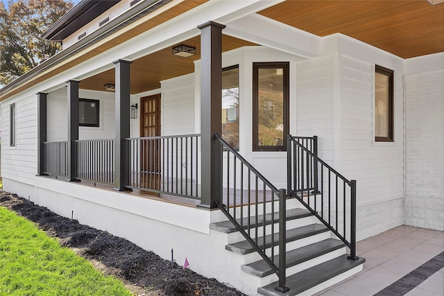 view of exterior entry with a porch and brick siding