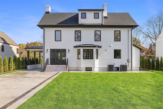 132 Arthur St, Garden City, NY 11530 - rear view of house with a chimney, concrete driveway, a lawn, a shingled roof, and entry steps