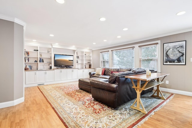 living room featuring crown molding, light wood-type flooring, and built in shelves