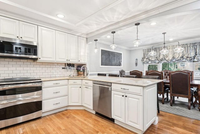 kitchen featuring stainless steel appliances, white cabinetry, pendant lighting, and kitchen peninsula