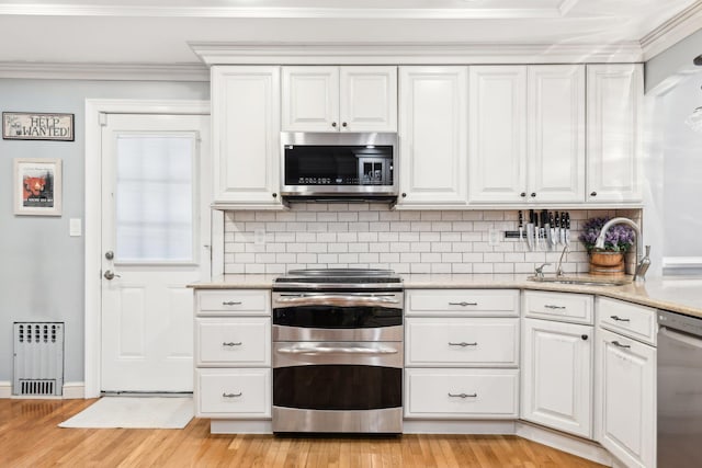 kitchen featuring white cabinetry, stainless steel appliances, light stone countertops, and sink