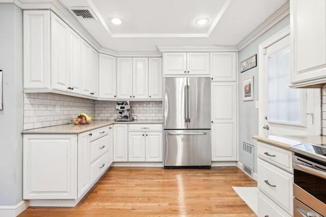 kitchen featuring white cabinets, decorative backsplash, light hardwood / wood-style floors, stainless steel appliances, and light stone countertops