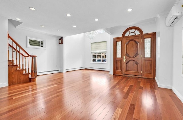 foyer entrance with hardwood / wood-style flooring, ornamental molding, a wall mounted AC, and a baseboard heating unit