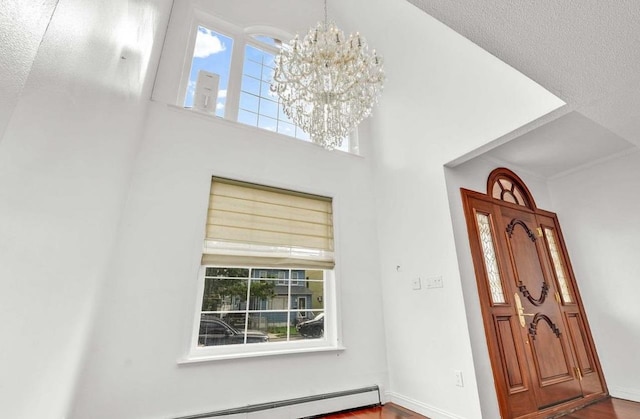 entryway featuring an inviting chandelier, wood-type flooring, and a baseboard heating unit