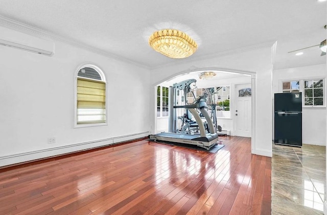 exercise area featuring a baseboard heating unit, hardwood / wood-style flooring, ornamental molding, and a wall mounted AC