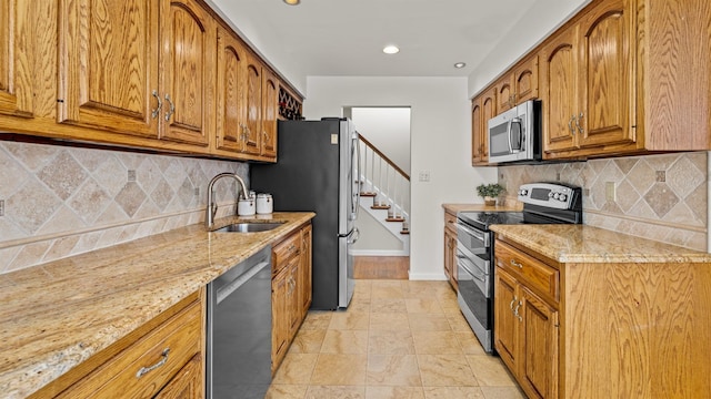 kitchen with light stone counters, appliances with stainless steel finishes, sink, and tasteful backsplash