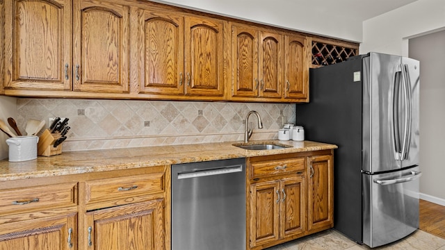 kitchen featuring appliances with stainless steel finishes, light stone countertops, sink, and decorative backsplash