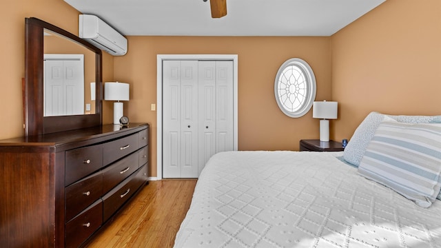 bedroom featuring ceiling fan, a closet, a wall unit AC, and light hardwood / wood-style flooring