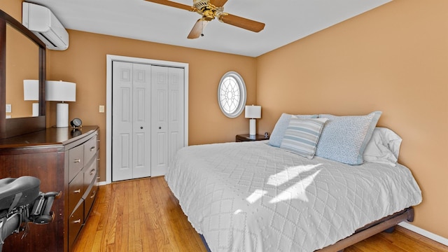 bedroom featuring a wall mounted air conditioner, a closet, ceiling fan, and light wood-type flooring