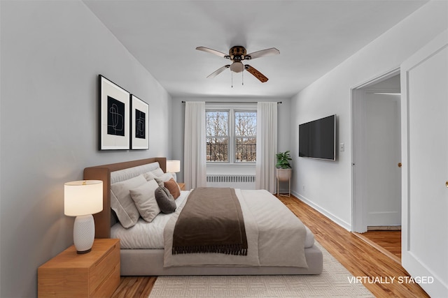 bedroom with ceiling fan, radiator, and light hardwood / wood-style floors