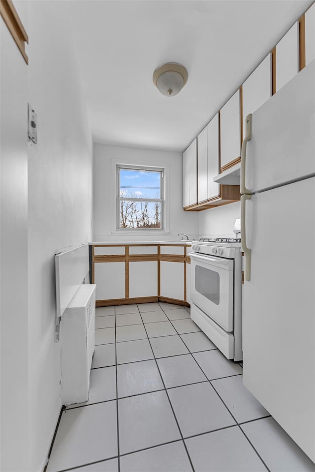 kitchen featuring light tile patterned floors, white appliances, and white cabinets