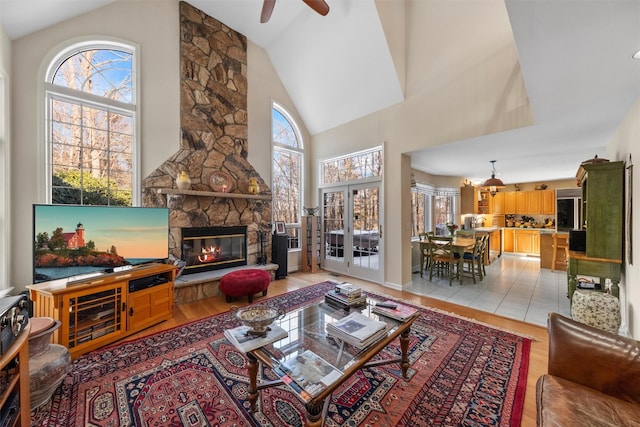 living room with a fireplace, high vaulted ceiling, and light wood-type flooring