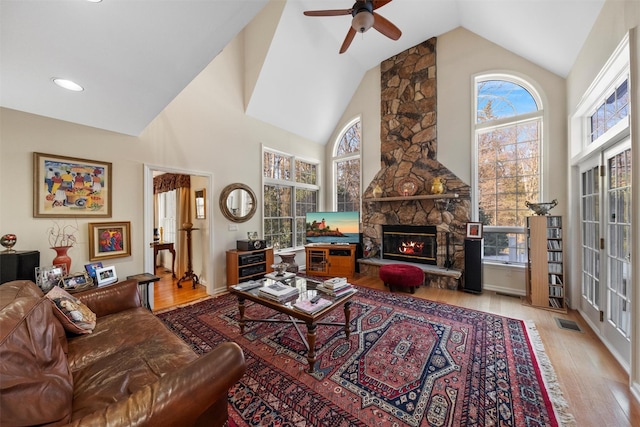 living room featuring a fireplace, high vaulted ceiling, and light wood-type flooring