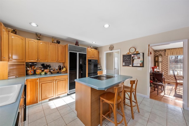 kitchen featuring light tile patterned floors, a breakfast bar, a center island, tasteful backsplash, and black appliances