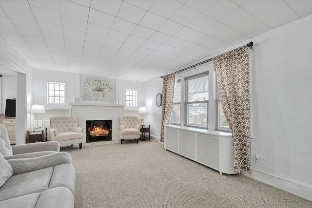 carpeted living room featuring a brick fireplace and radiator