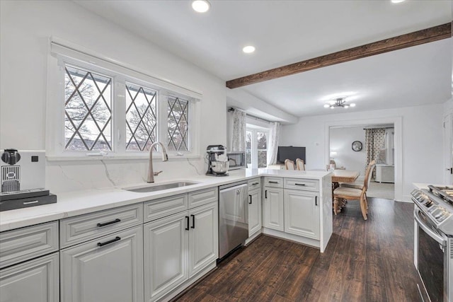 kitchen with sink, dark wood-type flooring, stainless steel appliances, white cabinets, and kitchen peninsula