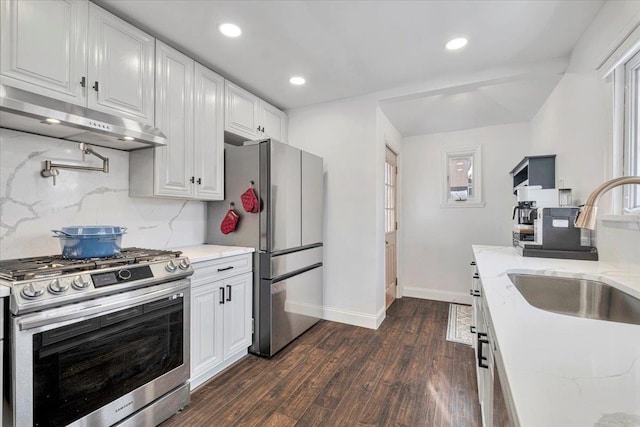 kitchen featuring dark wood-type flooring, white cabinetry, appliances with stainless steel finishes, light stone countertops, and decorative backsplash