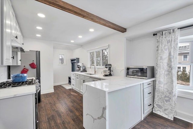 kitchen with kitchen peninsula, sink, light stone countertops, and white cabinets