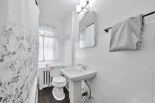 bathroom featuring hardwood / wood-style floors, a shower, tile walls, and toilet