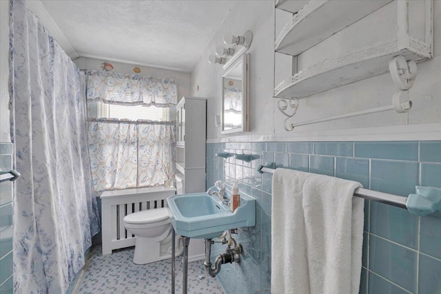 bathroom with tile walls, radiator, toilet, and a textured ceiling