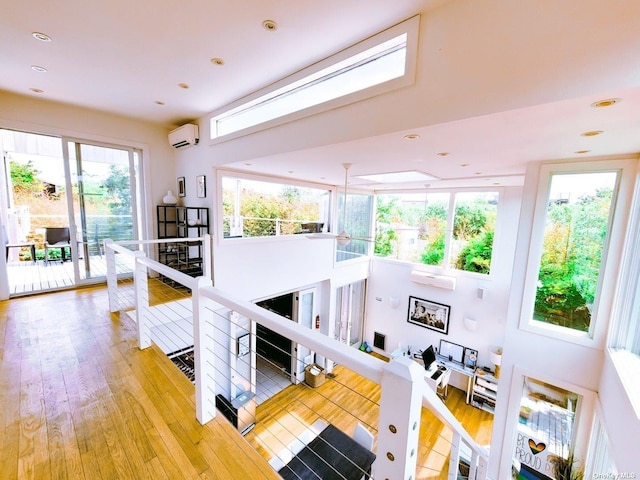 interior space with a wall mounted AC, hardwood / wood-style floors, and a high ceiling