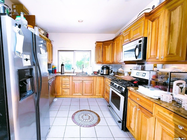 kitchen with light stone counters, stainless steel appliances, sink, and light tile patterned floors