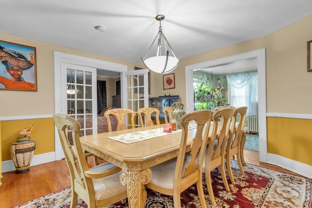 dining room with hardwood / wood-style flooring, radiator heating unit, and french doors