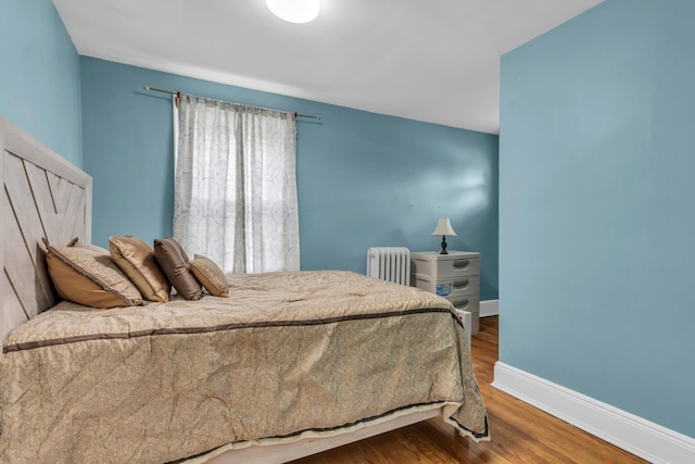 bedroom featuring radiator heating unit and wood-type flooring