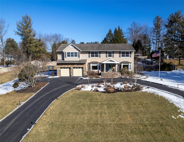 traditional-style home with an attached garage, stone siding, driveway, and a front yard