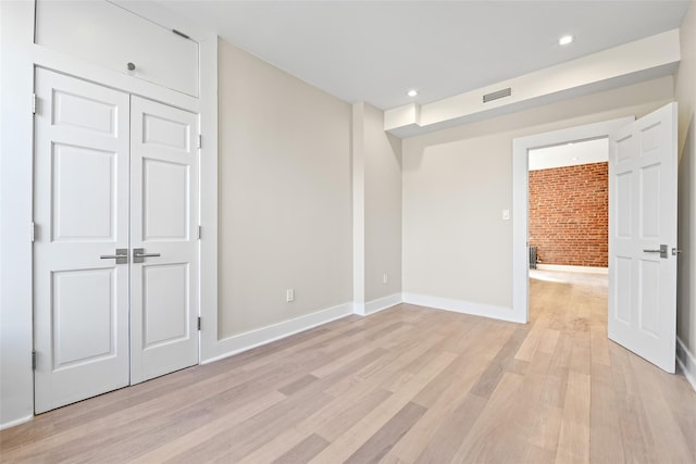 interior space featuring brick wall and light wood-type flooring