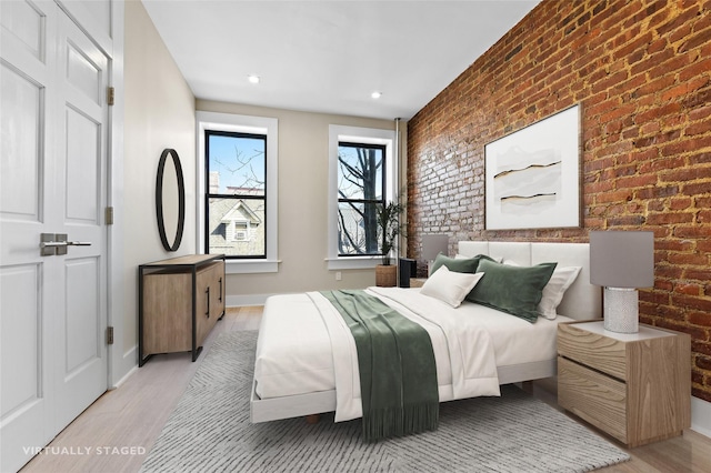 bedroom featuring brick wall and light wood-type flooring