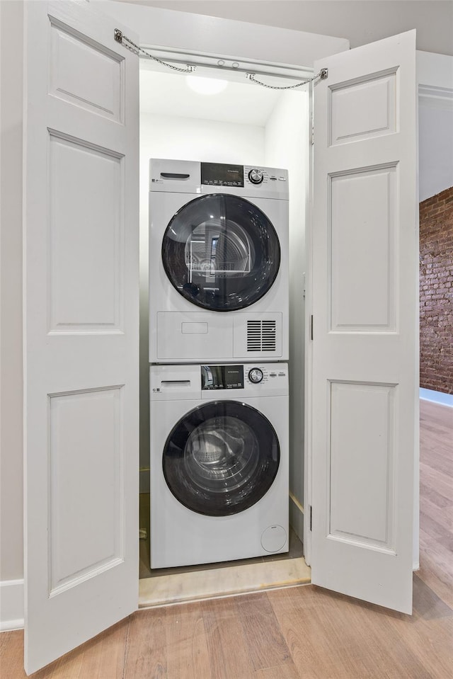 washroom with stacked washer and dryer and light wood-type flooring