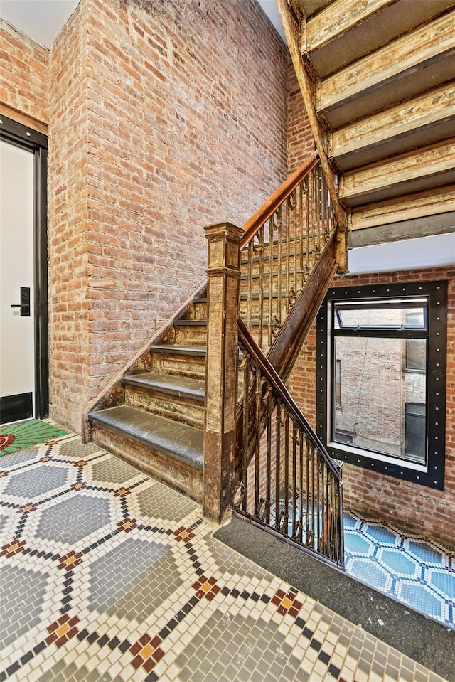 stairs featuring brick wall and a towering ceiling