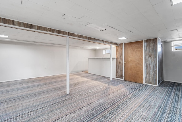 basement featuring carpet floors and wood walls