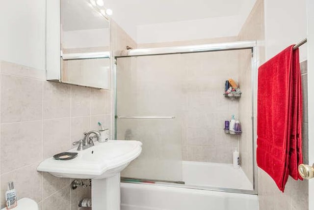 bathroom with tile walls and combined bath / shower with glass door