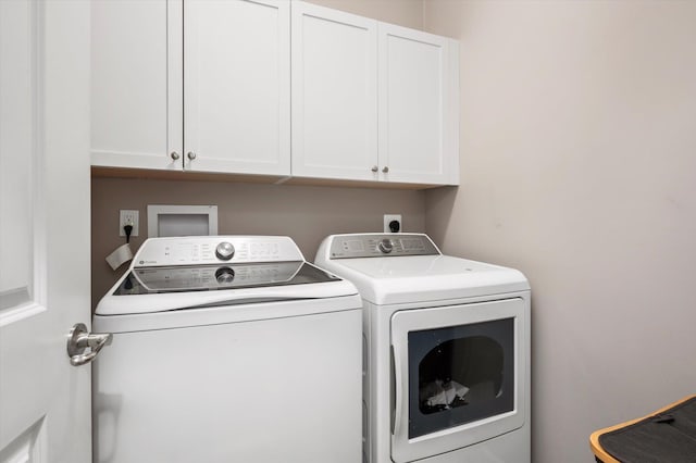 clothes washing area with washer and clothes dryer and cabinets