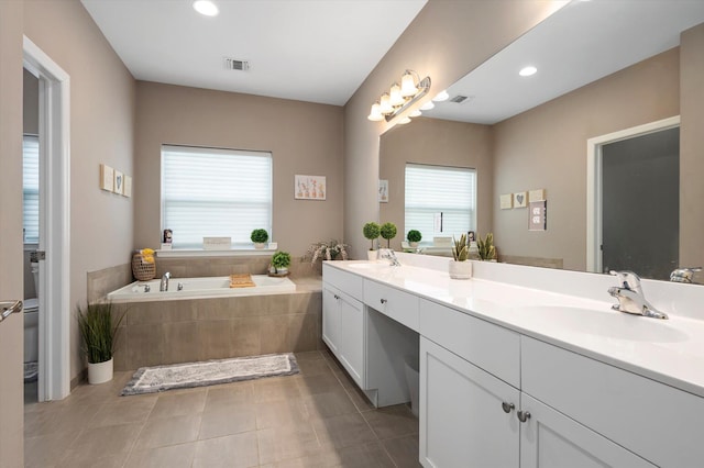 bathroom with vanity, tiled tub, and tile patterned flooring