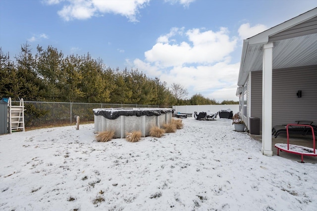 yard layered in snow featuring central AC unit, a covered pool, and a trampoline