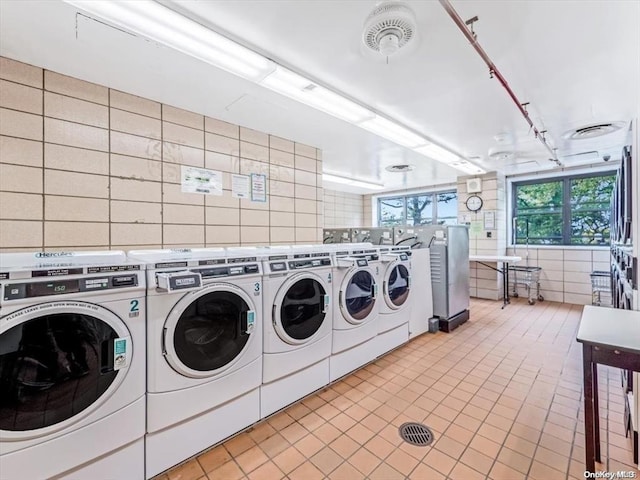 clothes washing area featuring washing machine and dryer, stacked washer and clothes dryer, and tile walls