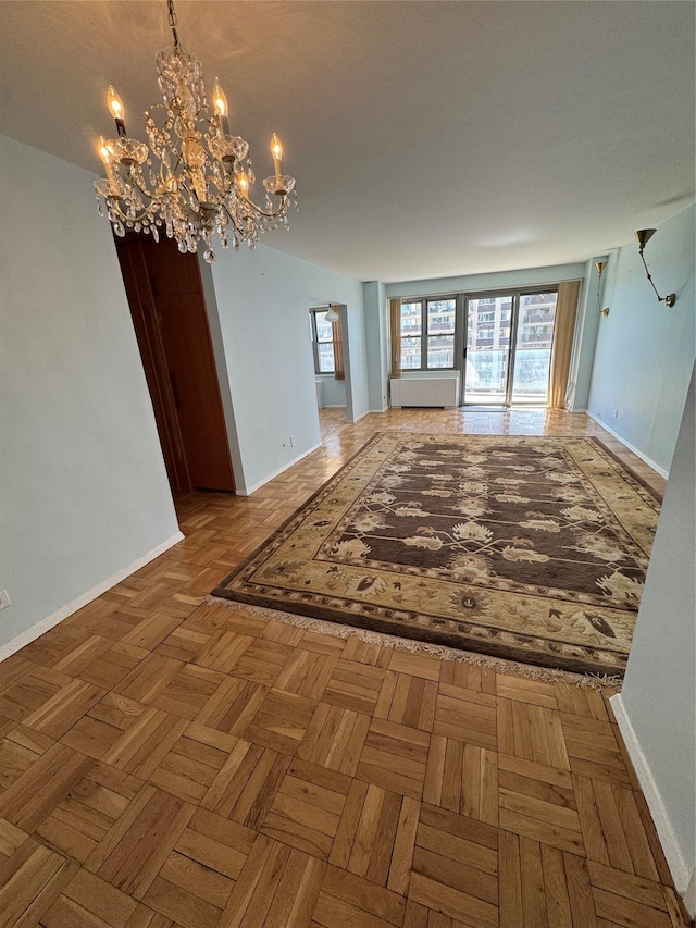 unfurnished room with baseboards and a chandelier