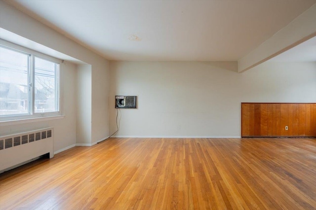 empty room with radiator, a wall mounted air conditioner, and light hardwood / wood-style floors