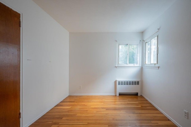 empty room featuring radiator heating unit and light hardwood / wood-style flooring