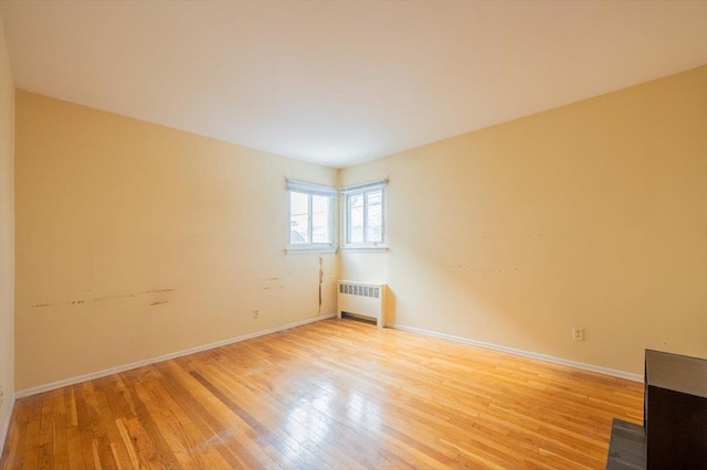 unfurnished room with radiator heating unit and light hardwood / wood-style flooring