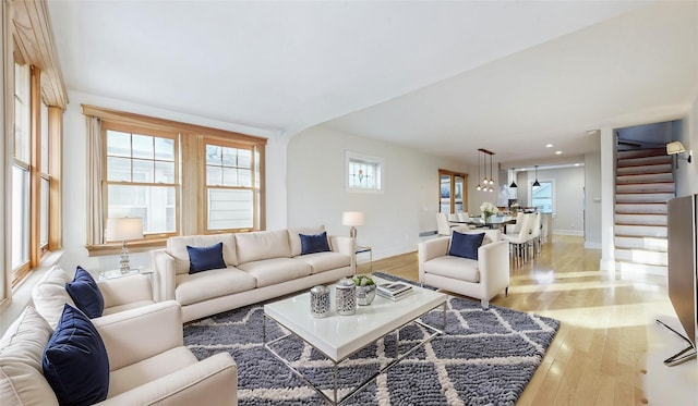 living room with stairway, light wood-type flooring, and baseboards